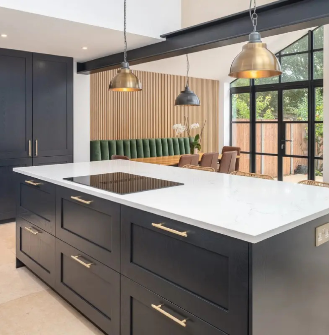 White quartz worktops on a modern kitchen island with dark cabinetry and gold hardware