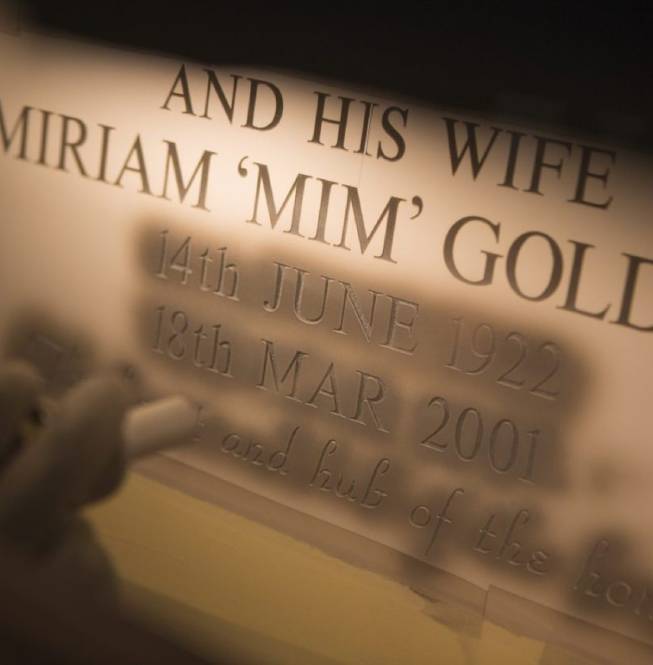 Stonemason engraving lettering into stone using a sandblasting technique.